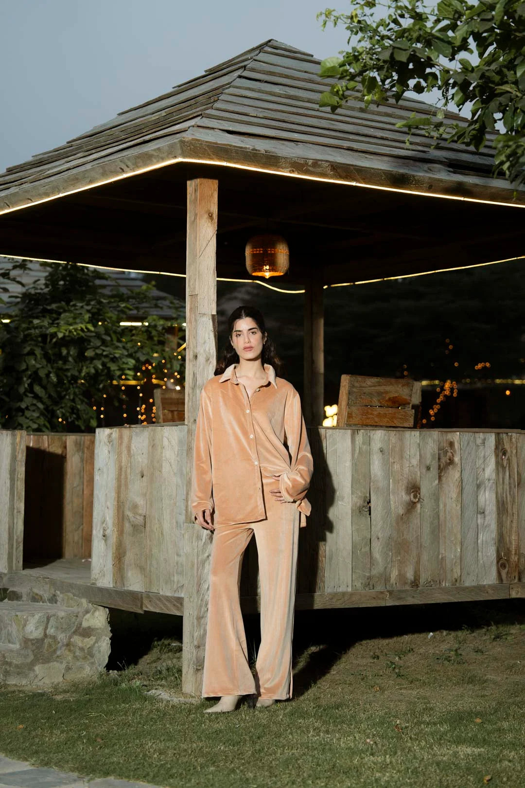 Full-body shot of tan velvet co-ord set showing shirt and straight trousers in natural light.