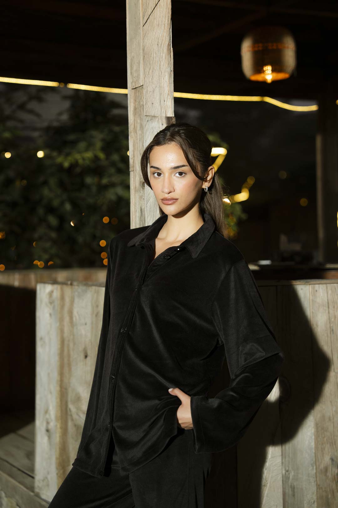 Full-length shot of black velvet co-ord set showing shirt and straight trousers in natural light.