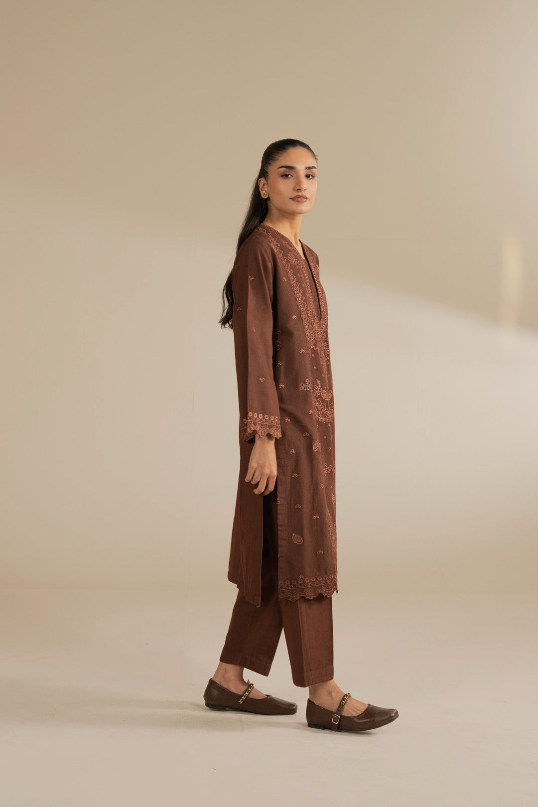 Full-length side/front pose of brown embroidered 2-piece suit showing complete look and drape.