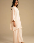 Full-length side/front pose of peach 2 piece suit showing straight trousers and hem finish.