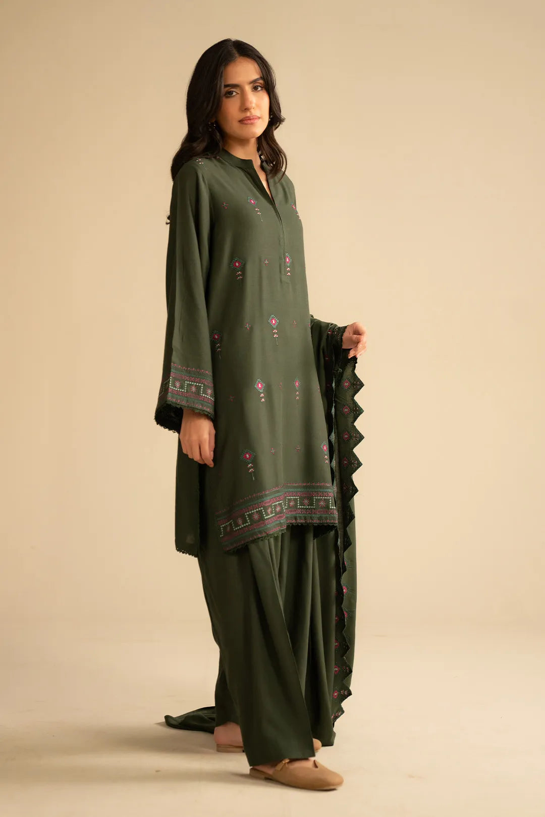 Full-length view of green embroidered linen suit with trousers and dupatta drape, showing overall silhouette.