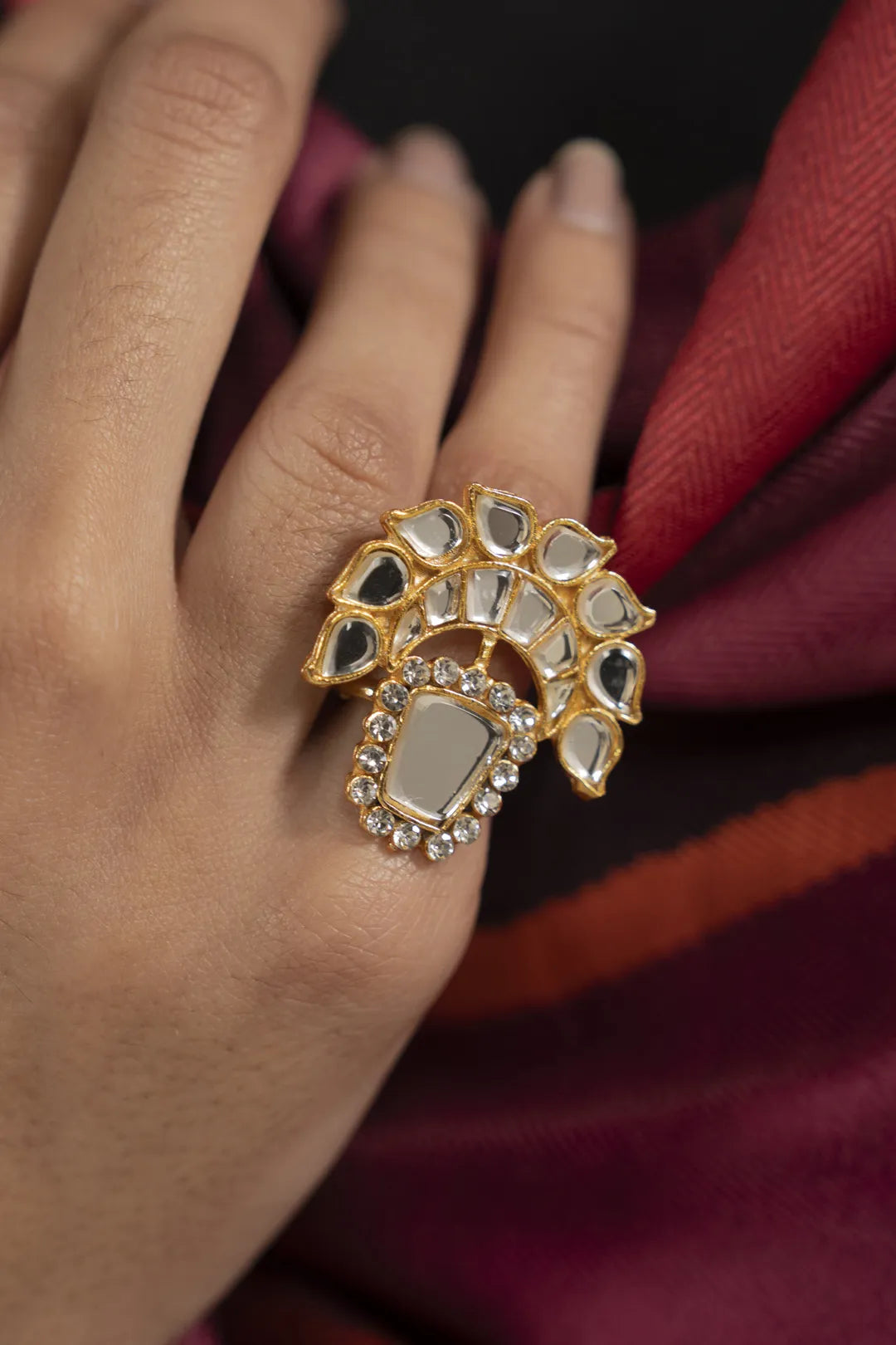 Gold-tone kundan statement ring on hand, sparkling stone cluster design (front view).