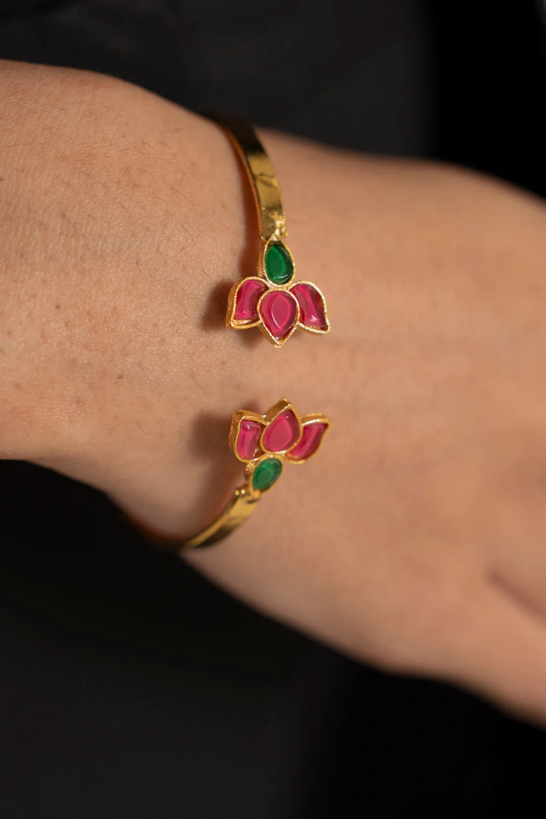 Hand wearing a gold-tone lotus kundan cuff bangle with pink floral motifs