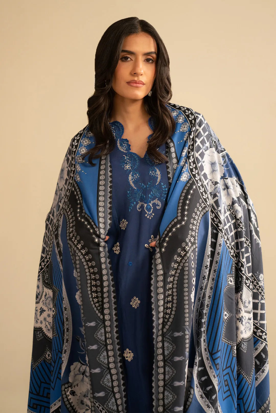 Model draped in printed shawl with royal blue embroidered suit, front pose showing border details
