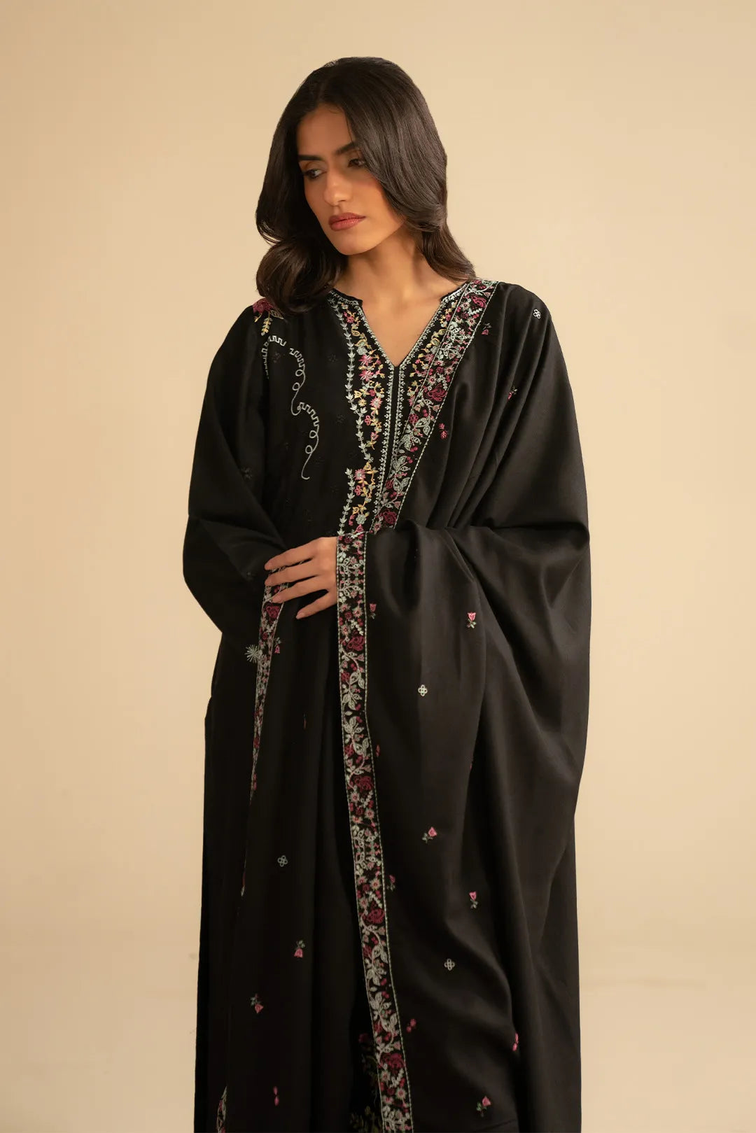 Model in black linen embroidered suit holding dupatta, showcasing pastel embroidery on kurta front