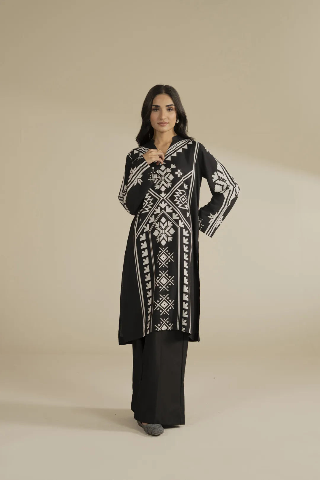 Model wearing a black printed linen shirt with white geometric motifs and black trousers, front full look