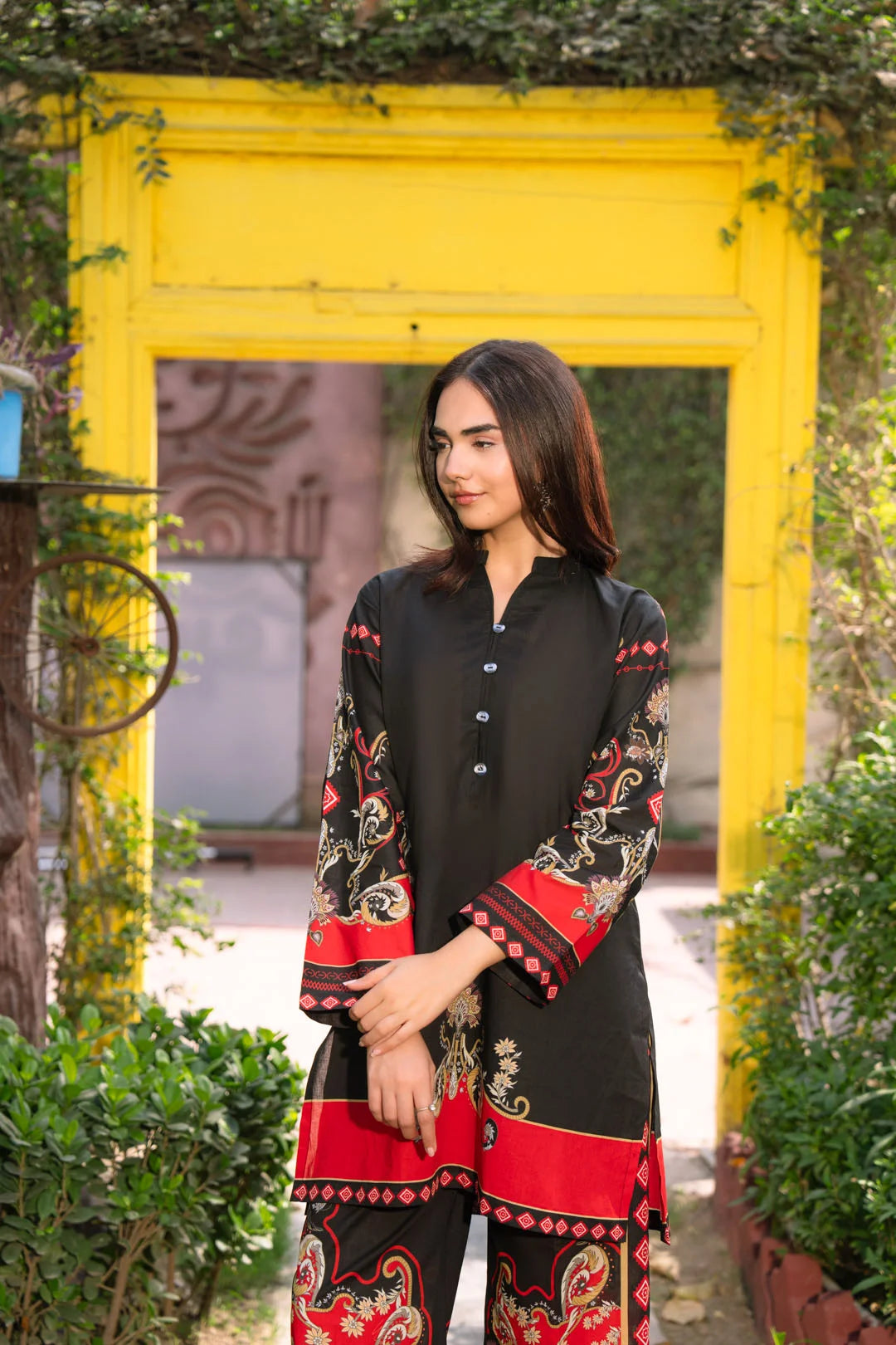 Model wearing black printed cambric pret suit with red trousers