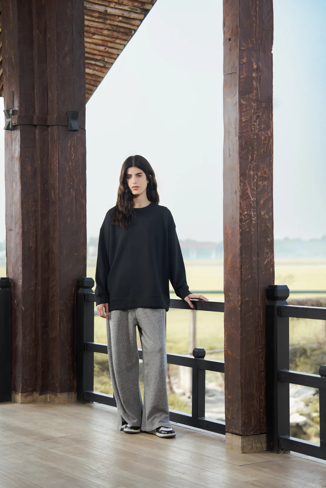 Model wearing black pullover sweatshirt with wide-leg pants, full length view