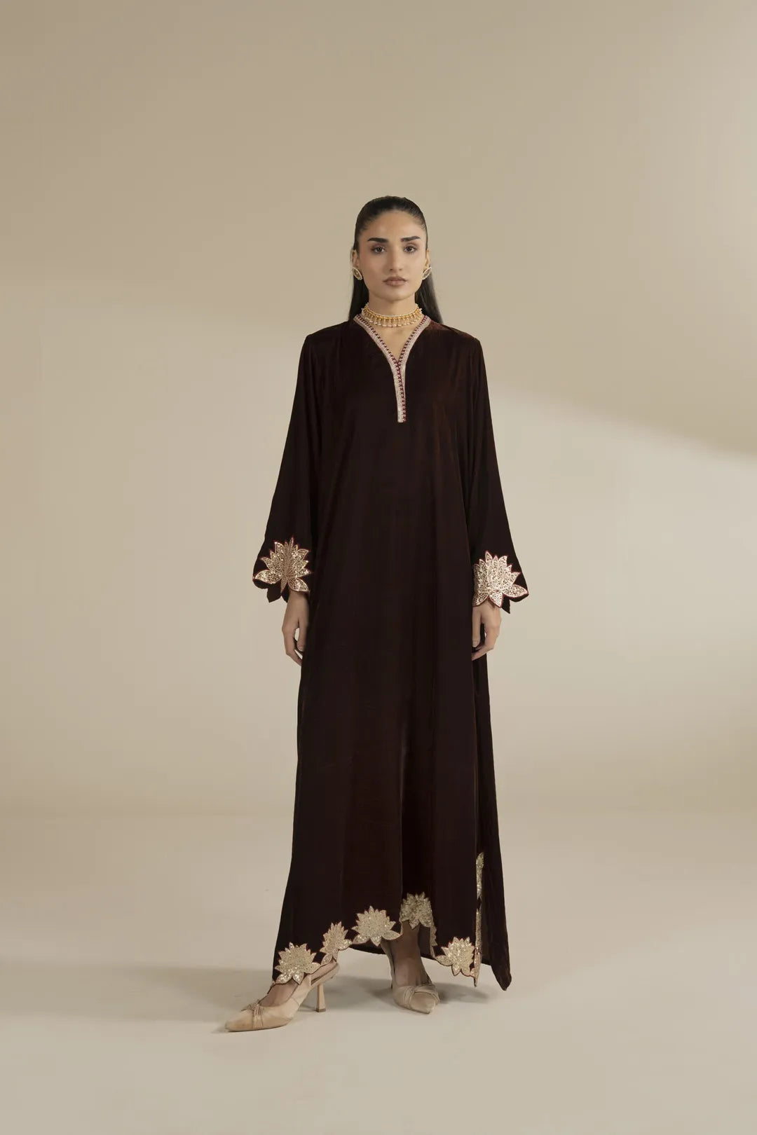 Model wearing black velvet embroidered kaftan with gold detailing, full-length front view in studio setting