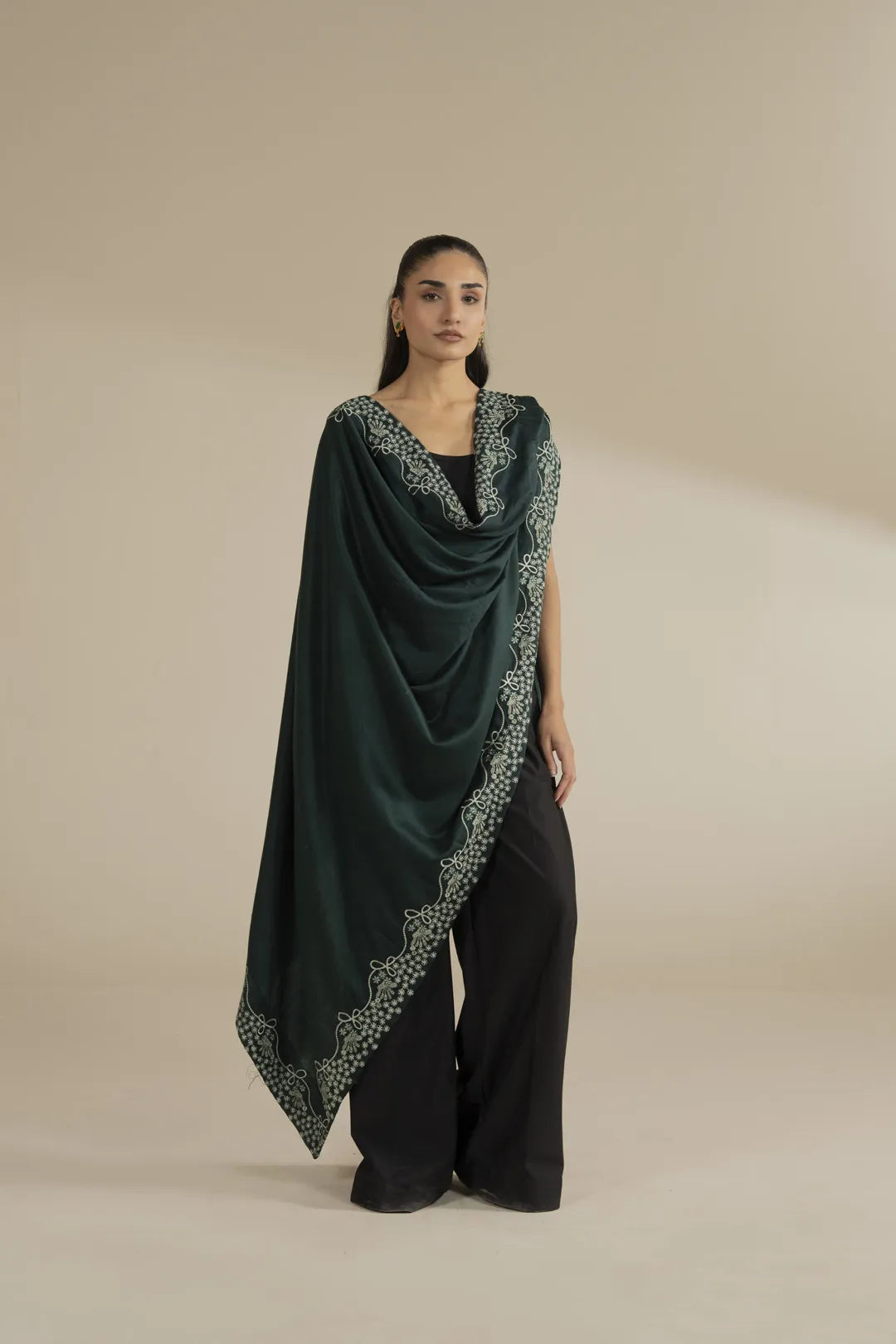 Model wearing dark green embroidered yarn dyed shawl draped over a black outfit, full front view in studio