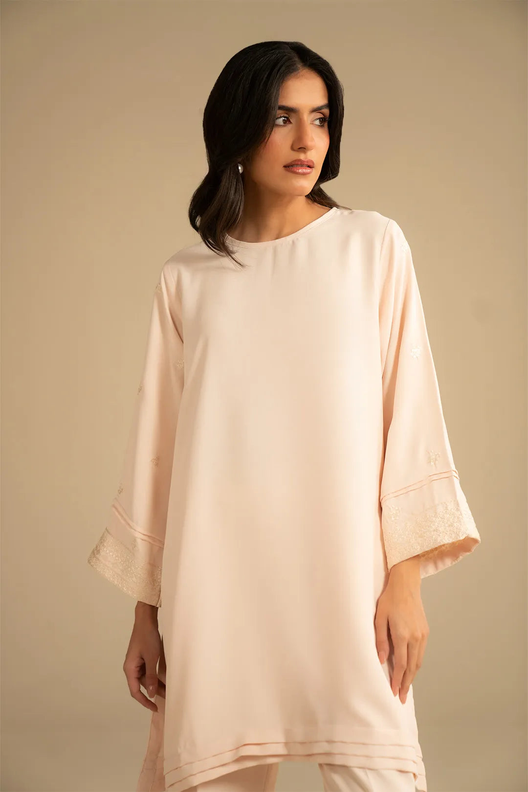 Model wearing peach 2 piece embroidered suit, full front view with relaxed kurta and straight trousers.