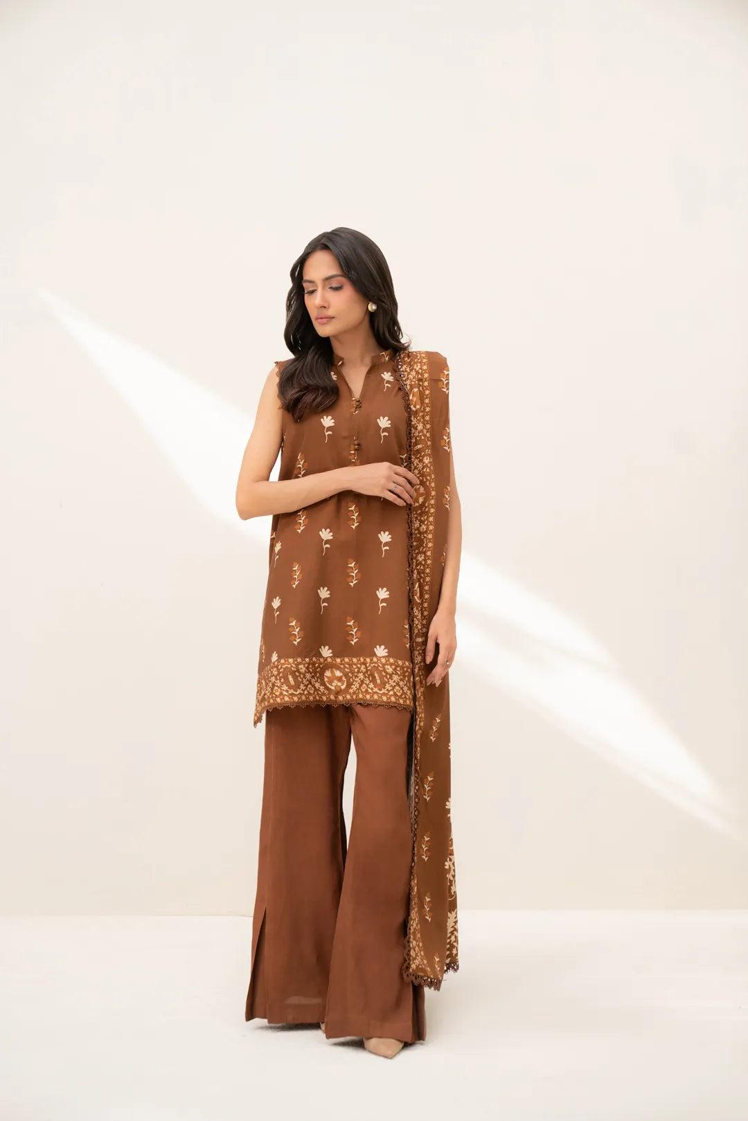 Model wearing rust brown printed linen 3-piece unstitched suit with matching dupatta