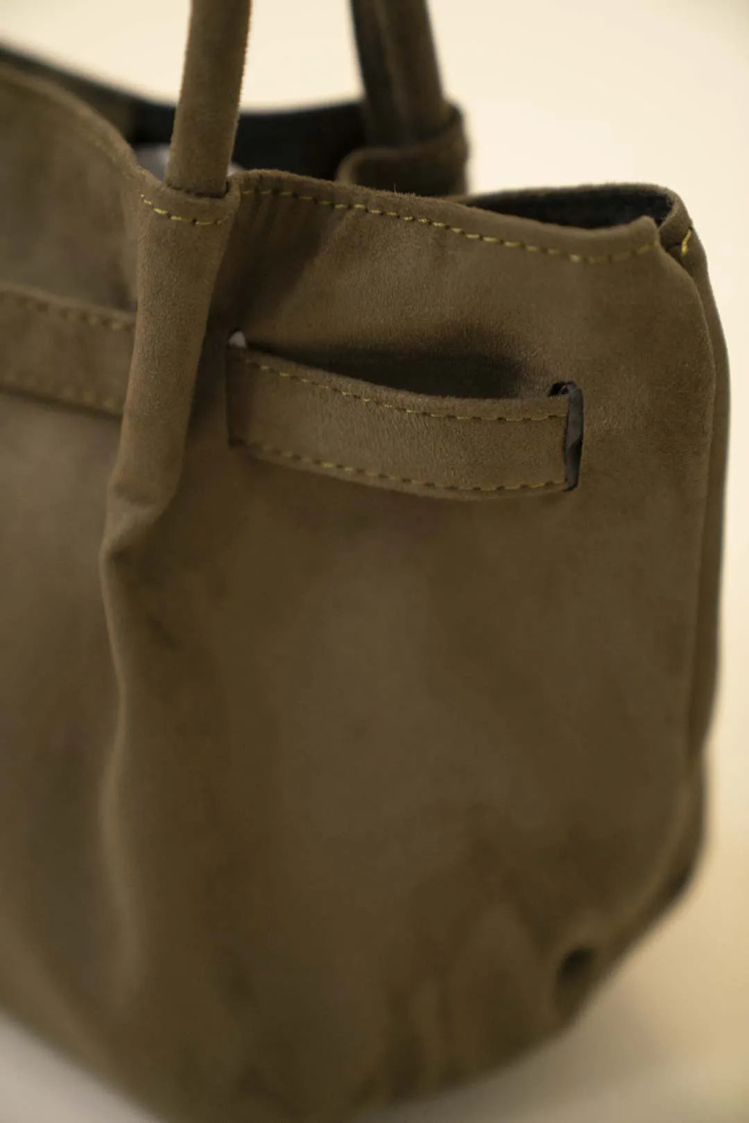 Olive green soft suede shoulder tote bag with structured base and long handles in studio lighting.