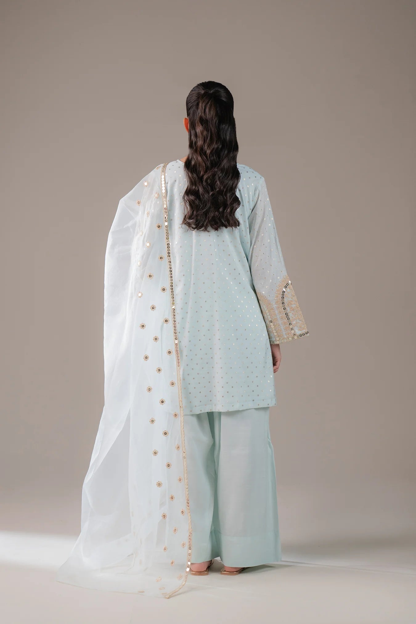 Pakistani 3 piece jamawar dress for women – modern light blue ethnic wear with golden threadwork and sheer dupatta, perfect for parties or cultural events abroad.
