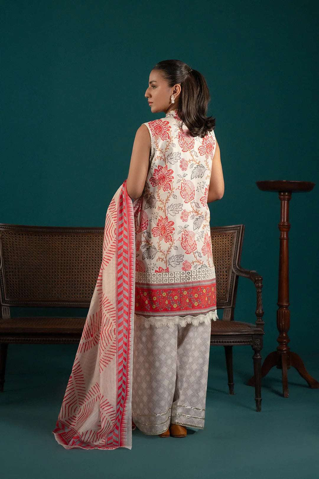 Pakistani lawn suits in vibrant colors – an off-white three-piece ensemble with abstract red prints, a printed dupatta, and stylish trousers.