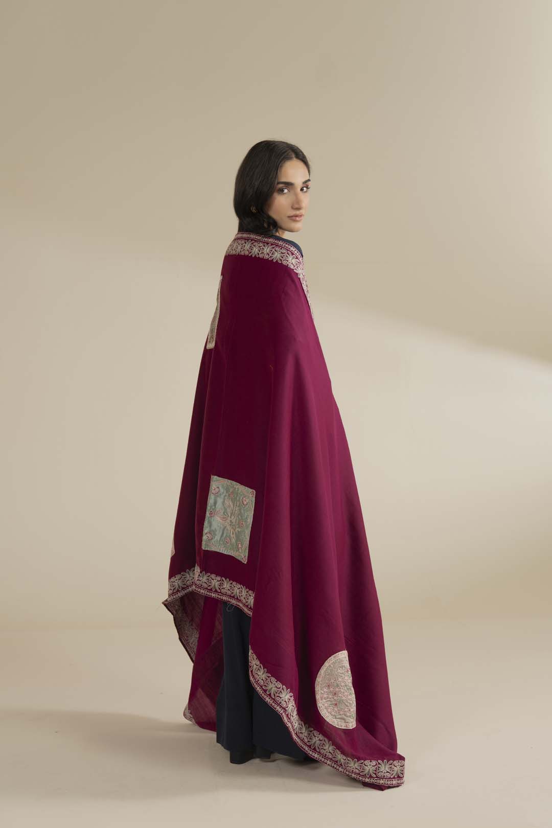 Patchwork motif panel on the shawl highlighted near the front drape, contrasted against dark clothing.