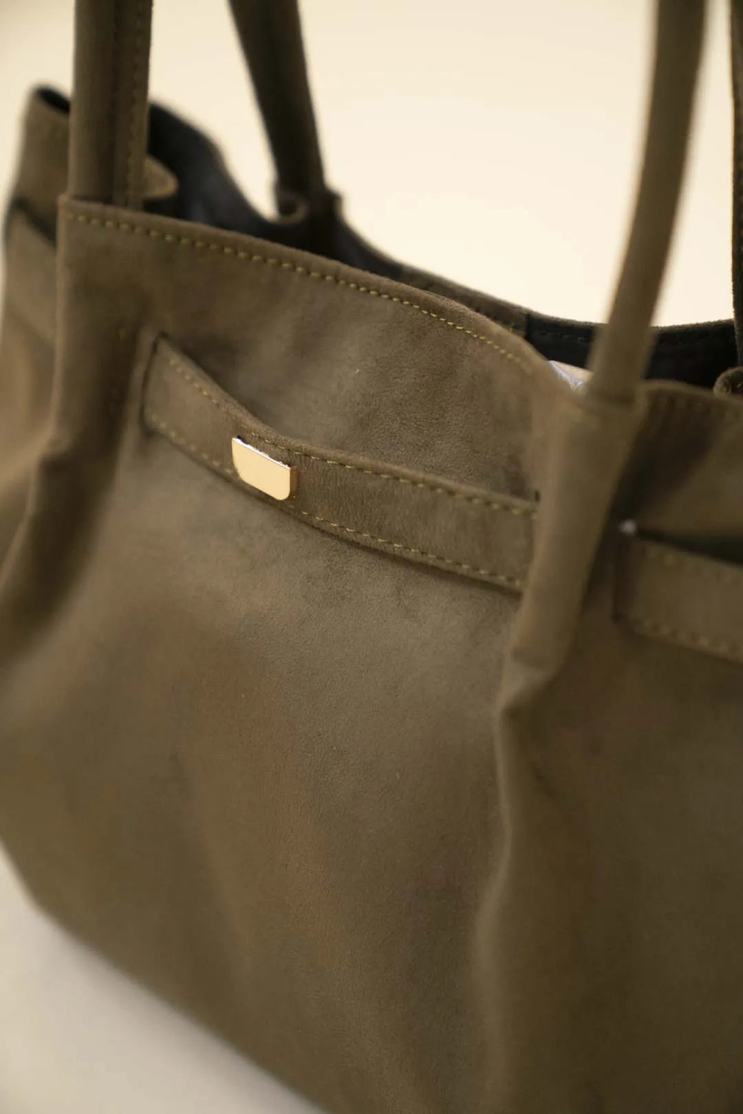 Side angle of olive green suede-look tote bag featuring minimal front strap detail and roomy shape.