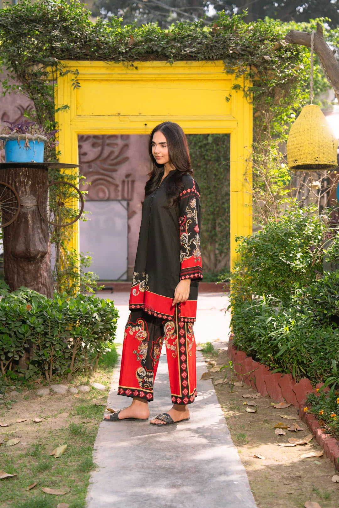 Side angle view of black printed cambric 2 piece suit with red printed bottoms
