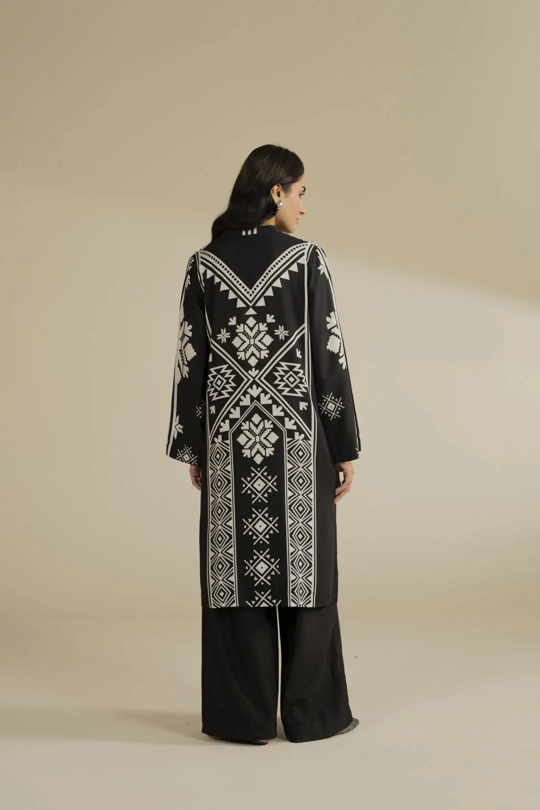 Side angle view showing the long hem and relaxed fit of the black printed linen shirt