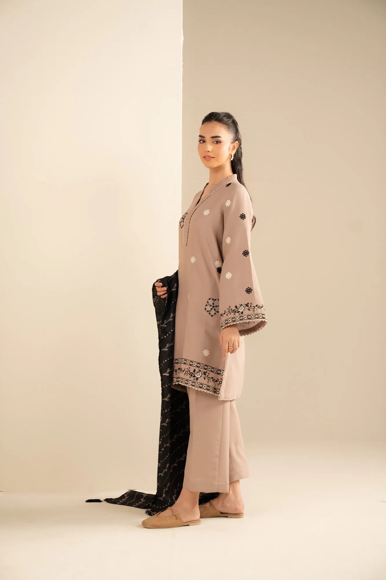 Side pose in skin-toned khaddar 3 piece suit with contrast black shawl