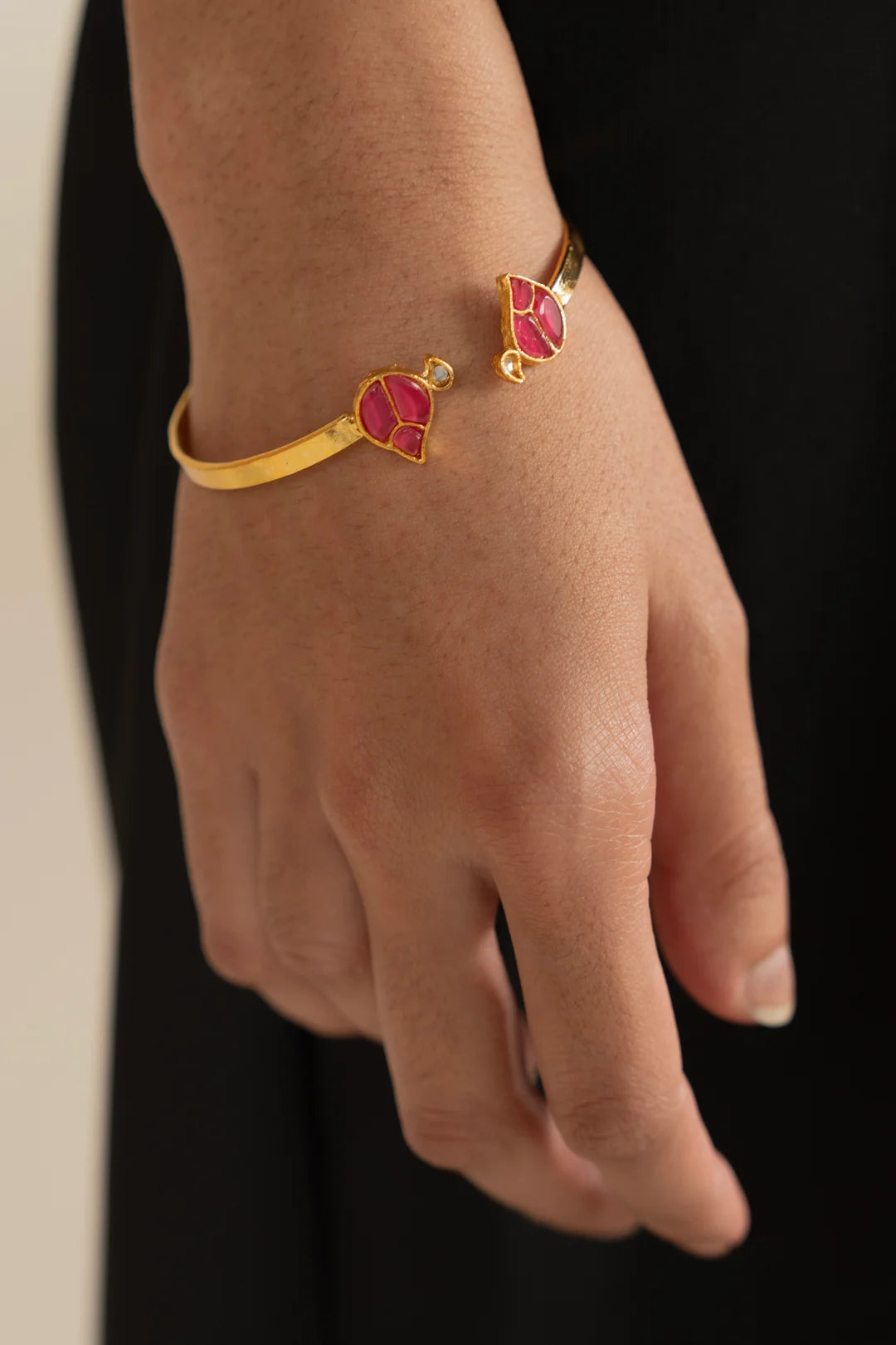 Side view of floral enamel cuff bangle showing slim band and bright pink detailing.