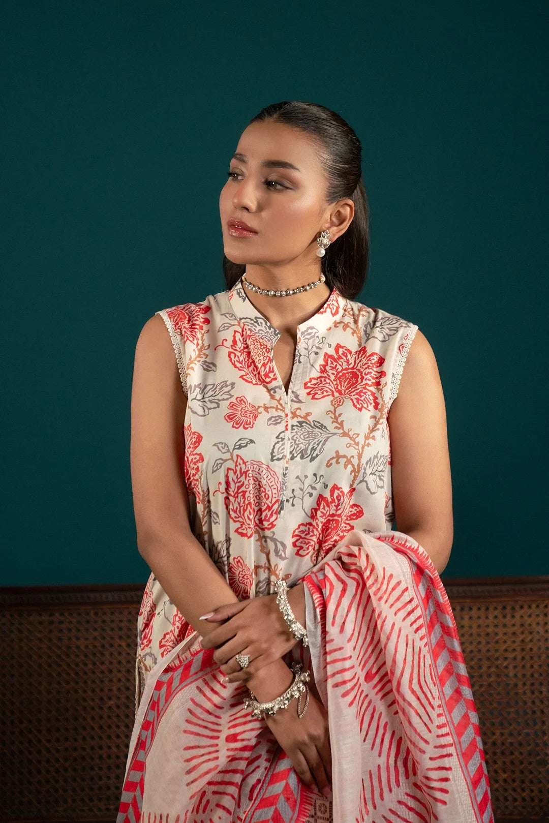 Stylish lawn suits for women – a printed off-white three-piece outfit with a contrasting cherry red dupatta and a composed border for a striking contrast.