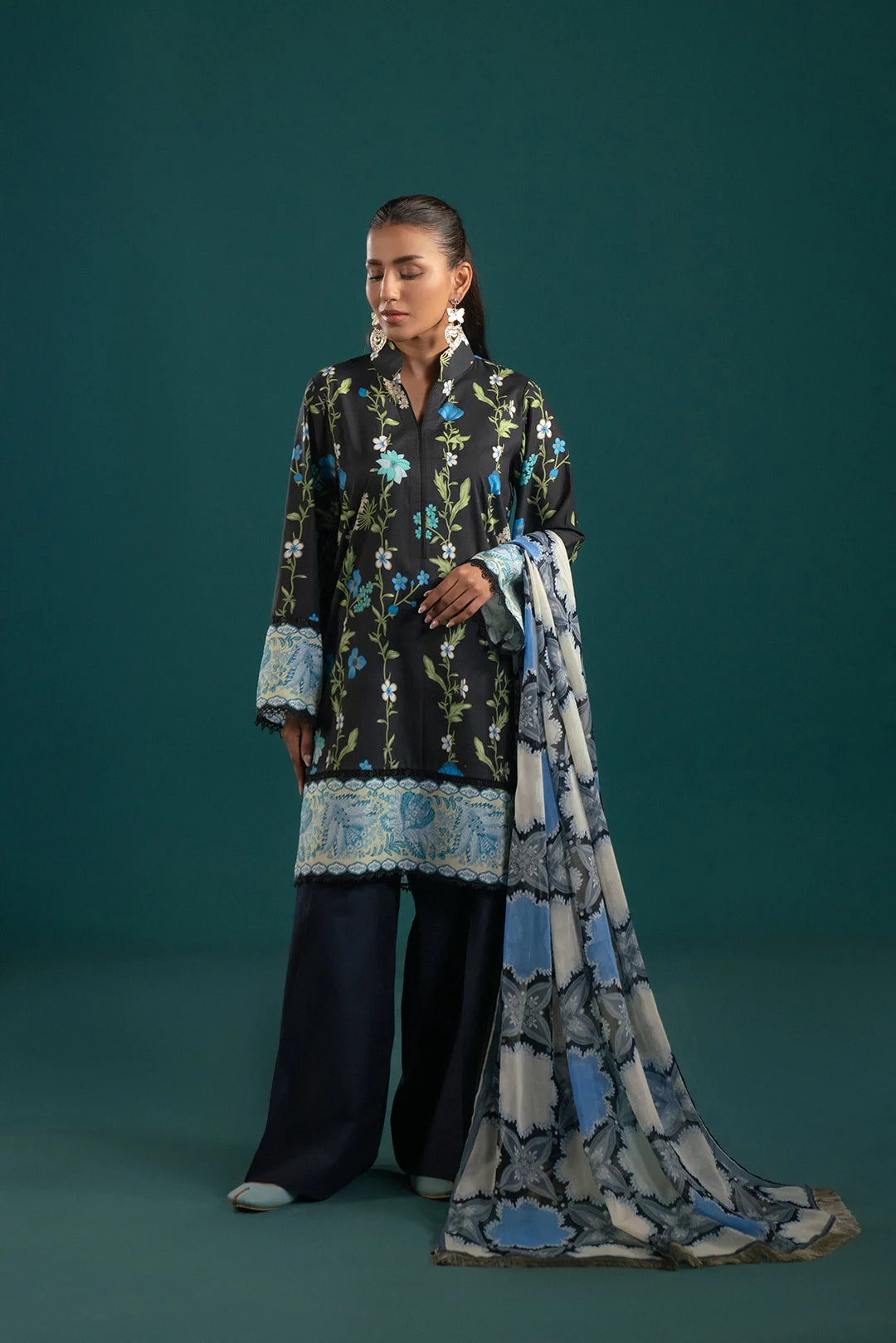 Stylish three piece lawn suit featuring a black floral-printed shirt, matching dyed cambric trouser, and a chiffon dupatta with modern abstract prints – perfect for summer fashion.