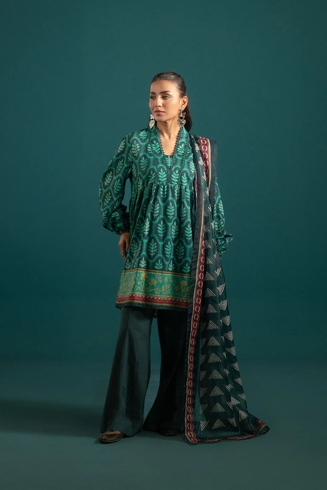 Trendy Green 3 Piece Lawn Suit with Printed Dupatta – A stylish Pakistani lawn suit featuring a deep green shirt with a nature-inspired leafy print, paired with dyed trousers and an elegant monark dupatta.