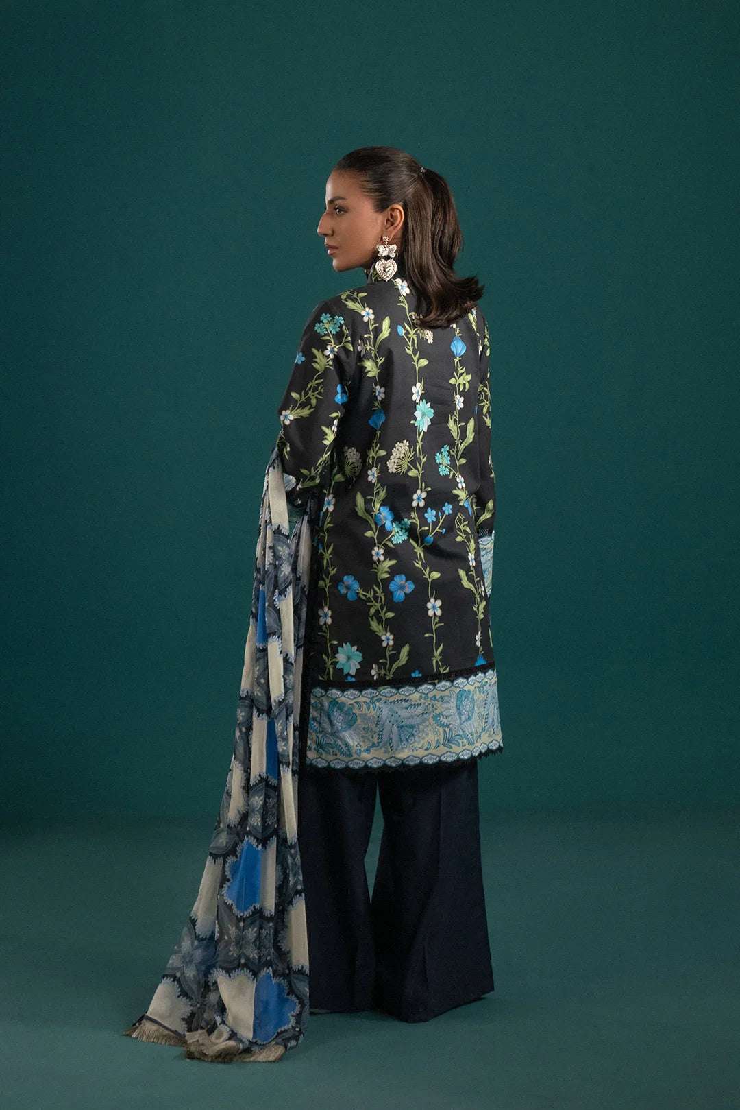 Trendy unstitched lawn suits online – 3 piece set with a vibrant floral black lawn shirt, complementing dyed trouser, and a blue abstract chiffon dupatta.
