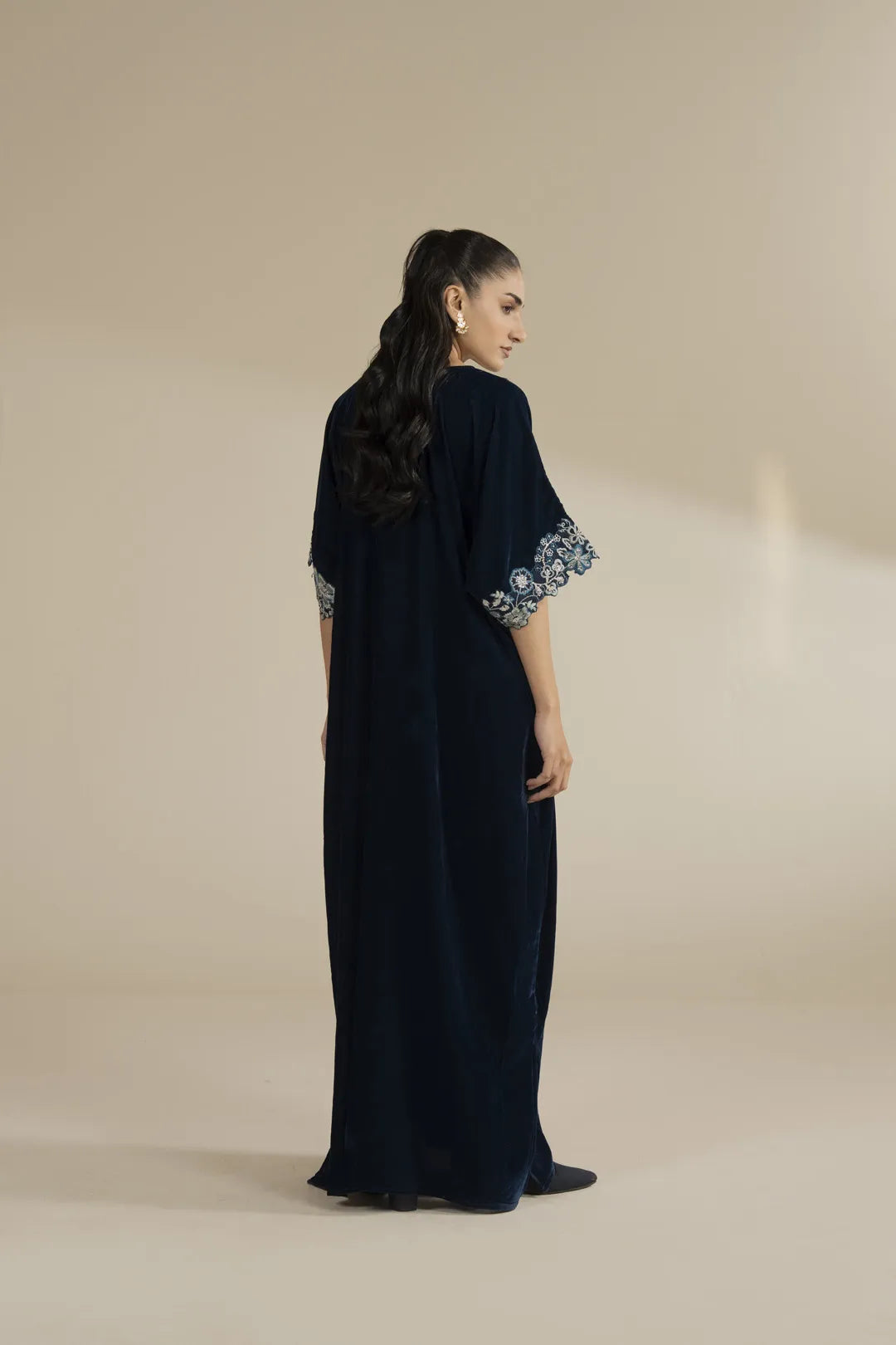 Wide studio view of the velvet kaftan emphasizing minimal silhouette and embellished neckline.