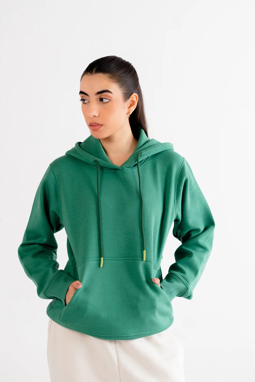 Woman wearing a basic green hoodie with adjustable drawstrings and a front pocket, perfect for casual wear.