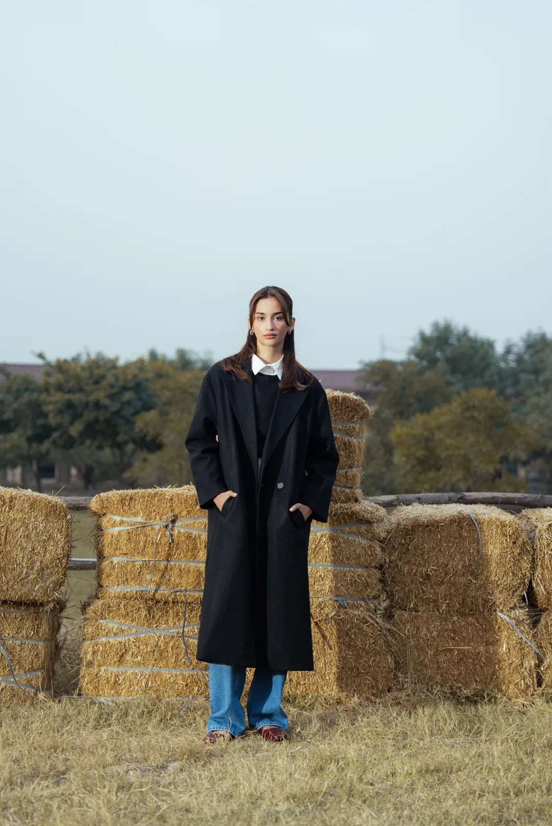 Woman wearing a black long winter coat outdoors, full-length front view