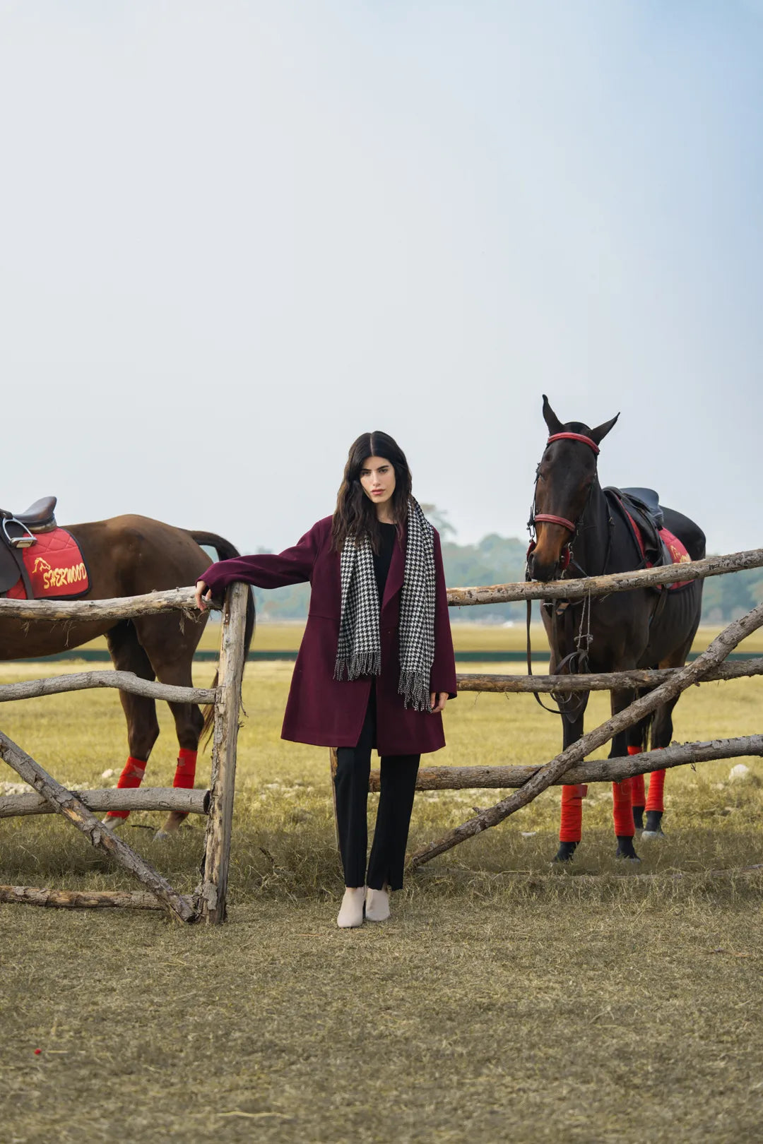 Woman wearing a maroon knee-length winter coat outdoors, full-length front view