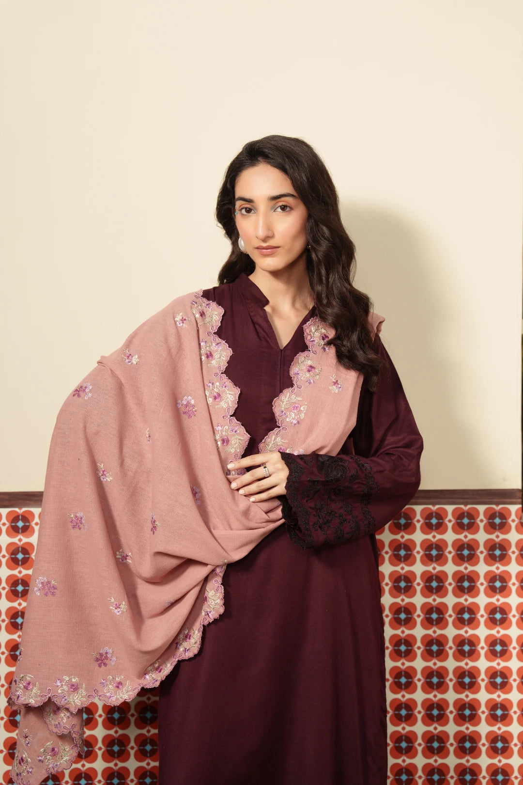 Woman wearing a dusty pink embroidered viscose shawl draped over a maroon outfit, featuring intricate floral needlework along the border